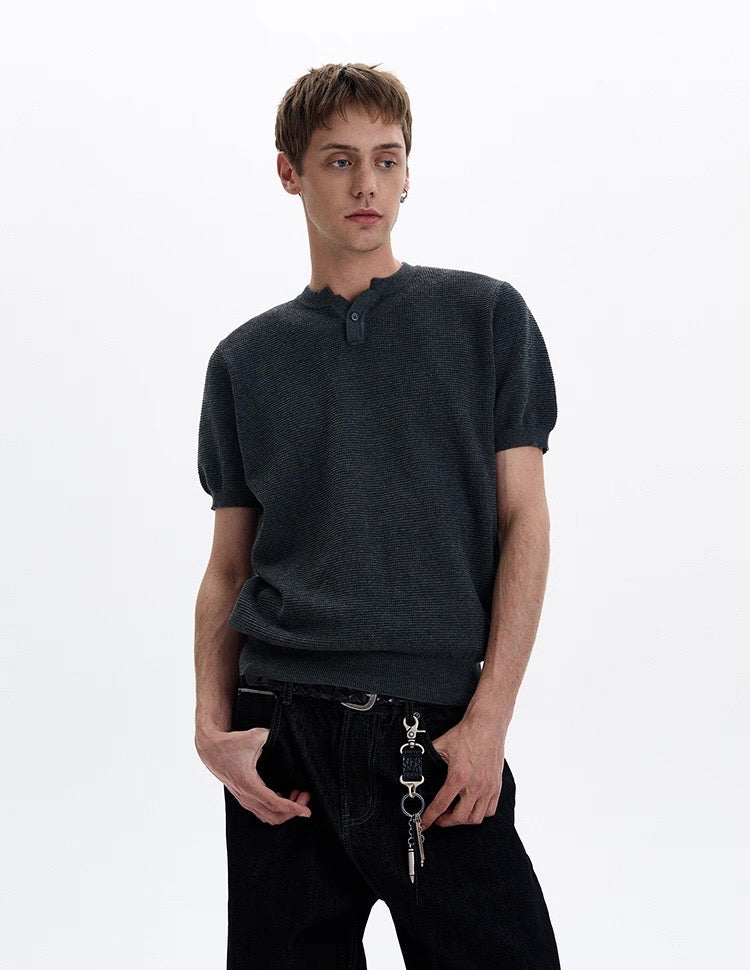 Dark textured knit short sleeve polo tee styled on a model with a relaxed fit and buttoned collar