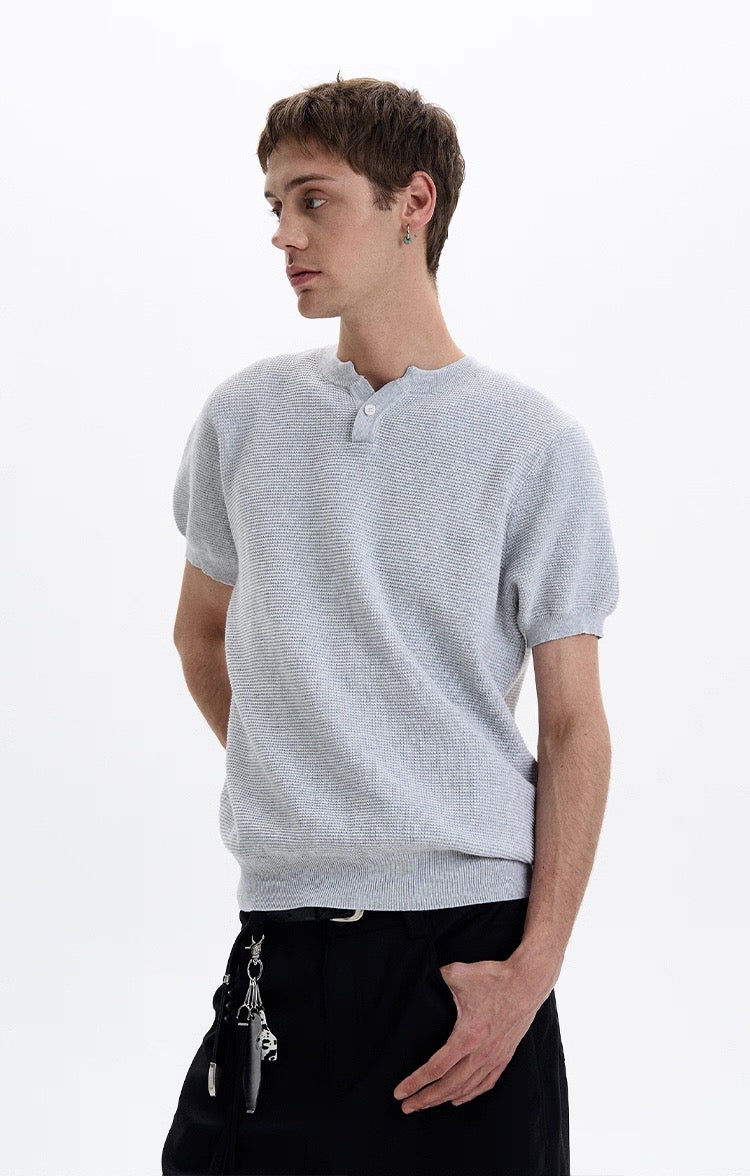 Light gray textured knit short sleeve polo tee with a relaxed fit and buttoned neckline on a male model