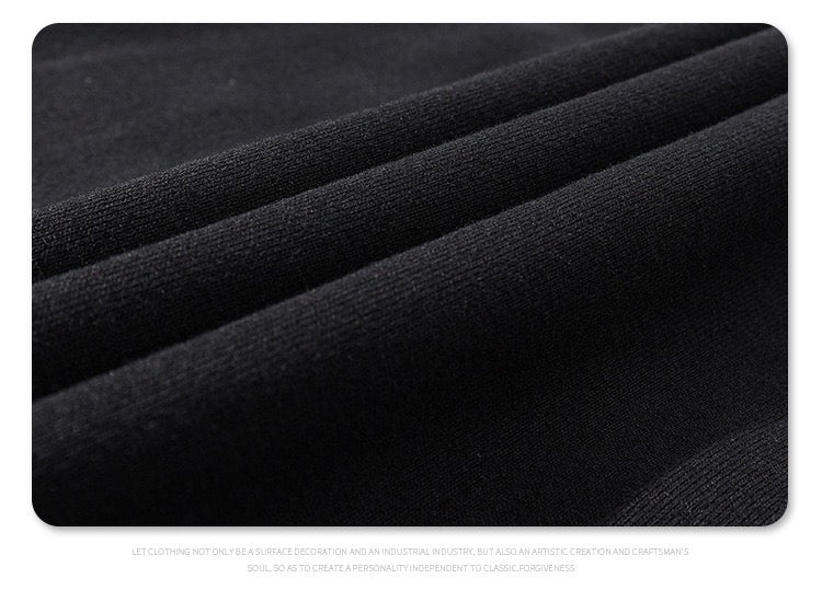Close-up of black textured fabric with subtle ribbed panels, showing the oversized streetwear T-shirt material detail