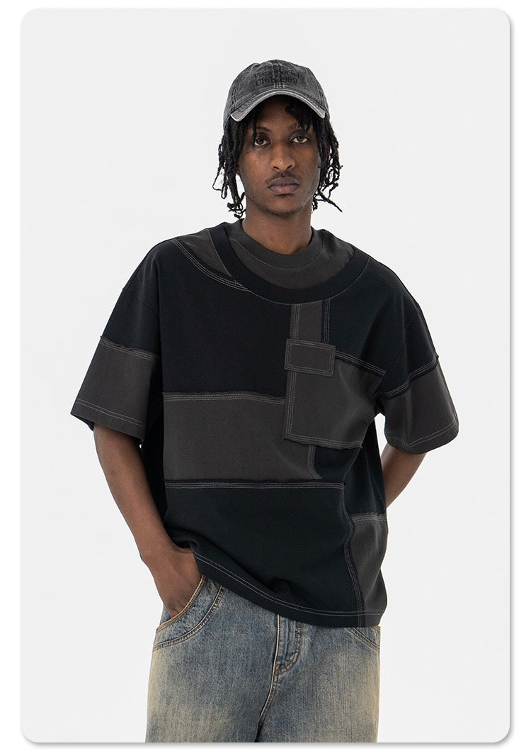 Black oversized patchwork panel T-shirt with contrast stitching, worn by a male model in streetwear style