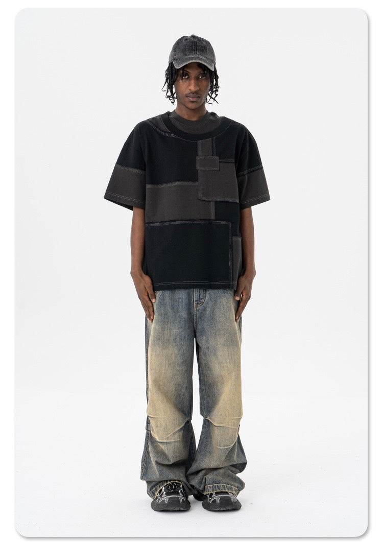Black oversized patchwork T-shirt with deconstructed panel design styled with baggy faded jeans and a black cap