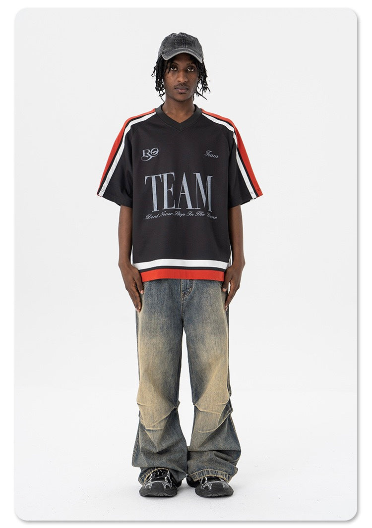 Model wearing a black oversized varsity mesh tee with red and white stripes, paired with baggy faded jeans and sneakers