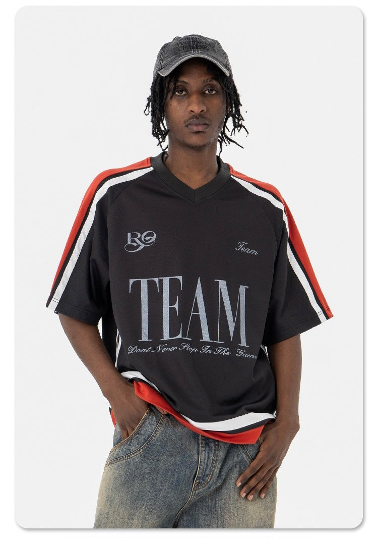 Oversized black varsity mesh tee with red and white shoulder stripes, team graphic, and relaxed sportwear fit on model