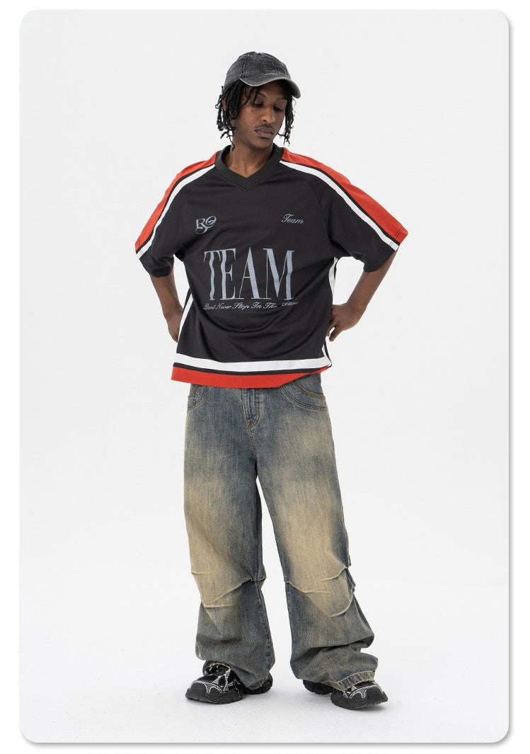 Black oversized varsity mesh tee with red and white sleeve stripes, worn with baggy faded jeans and cap