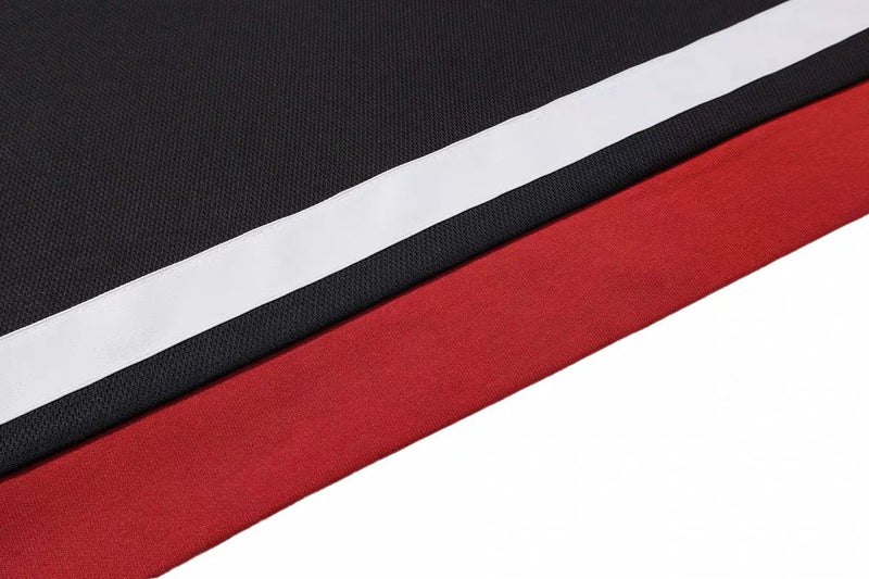 Close-up of black and red mesh tee fabric with a bold white stripe, showing retro varsity sportwear texture