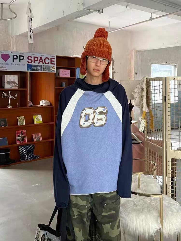 Model wearing blue and navy colorblock raglan hoodie with 06 graphic, front view
