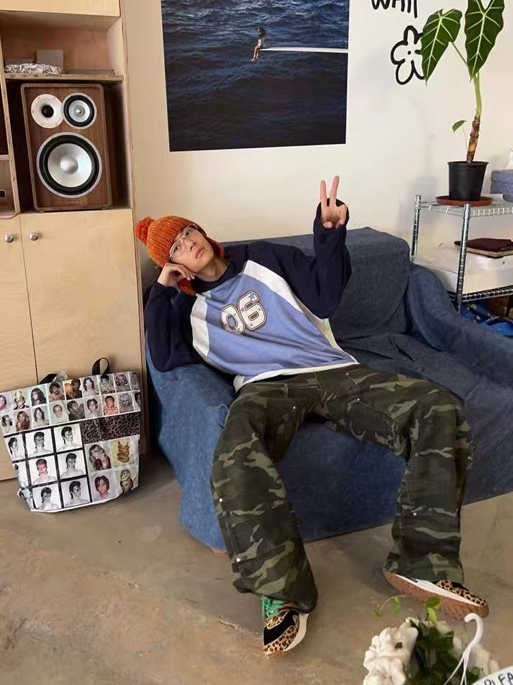 Model reclining in blue and navy colorblock hoodie with 06 graphic, front view