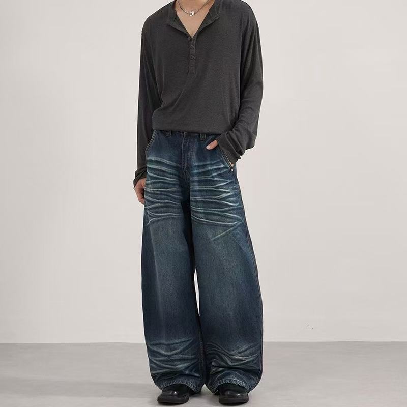 Front view of dark blue baggy jeans with faded whisker details and wide legs