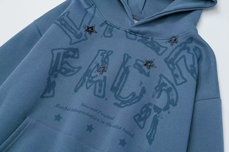 Blue hoodie front close-up showing distressed graphic text and star embellishments