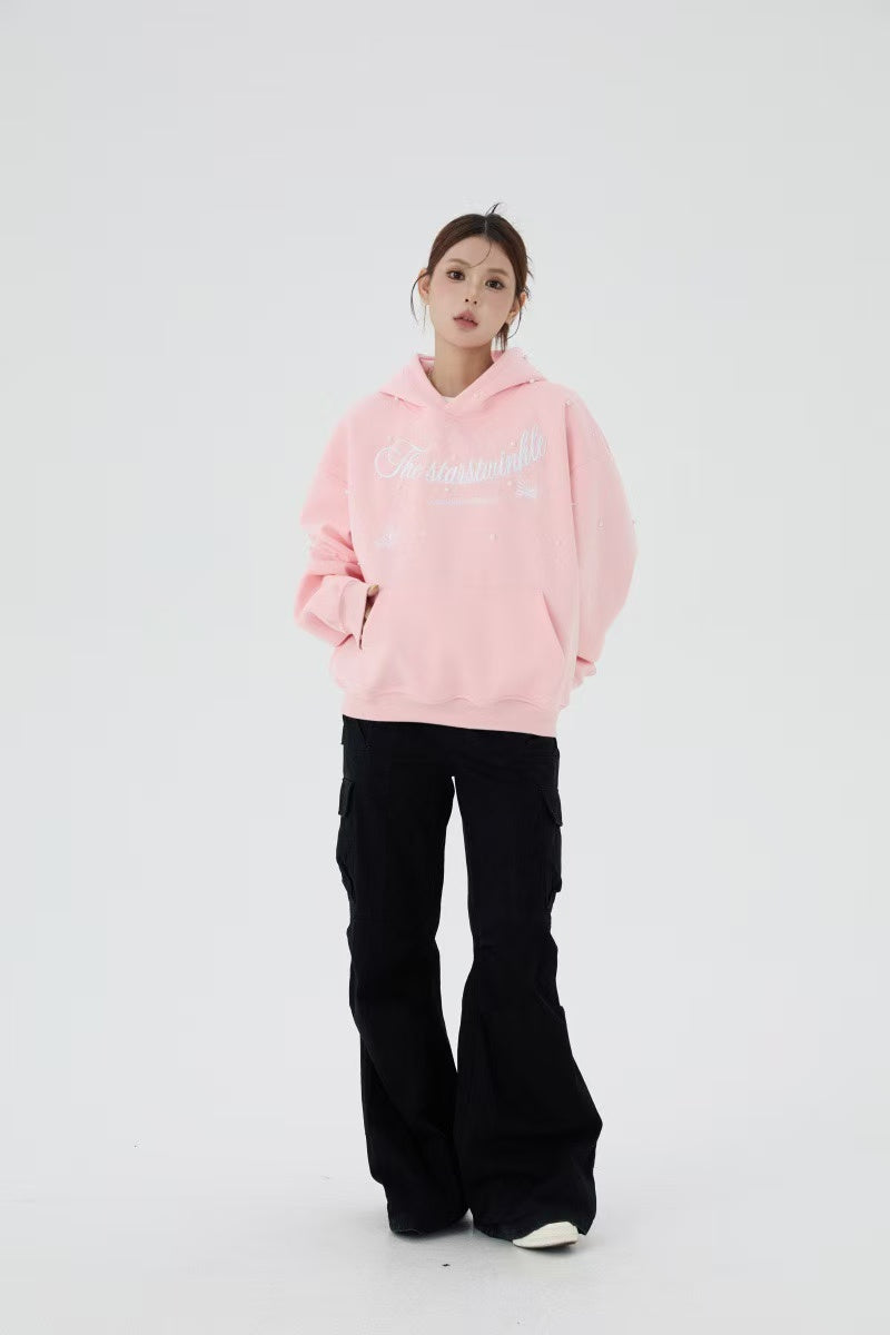 Pink pearl embellished hoodie worn by model, full-body front view