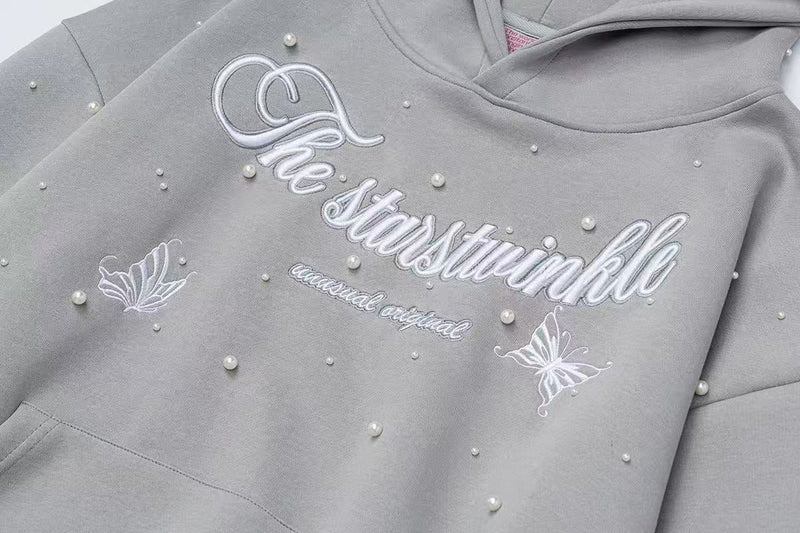 Close-up of gray hoodie front showing script embroidery and pearl embellishments