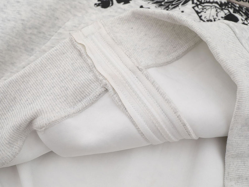 Close-up of light gray hoodie zipper, sleeve cuff, and interior seam detail