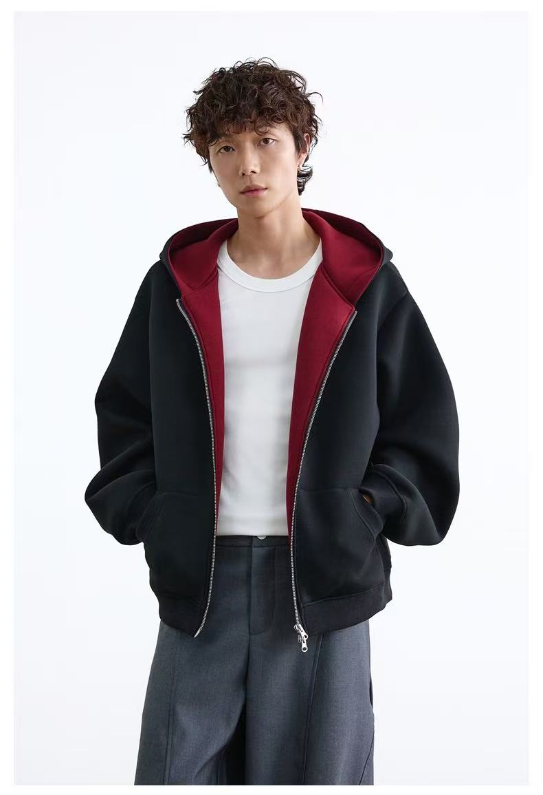 Model wearing black oversized zip-up hoodie with maroon hood lining