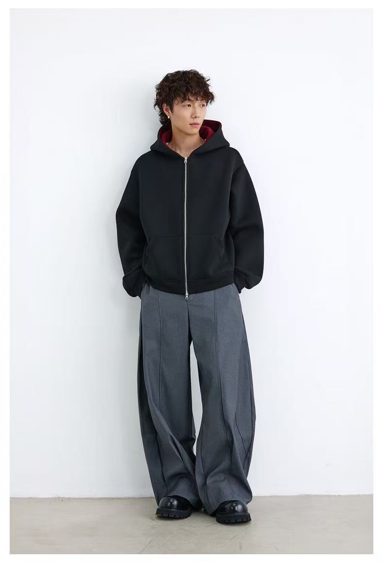 Front view of model wearing black oversized hoodie with maroon hood lining