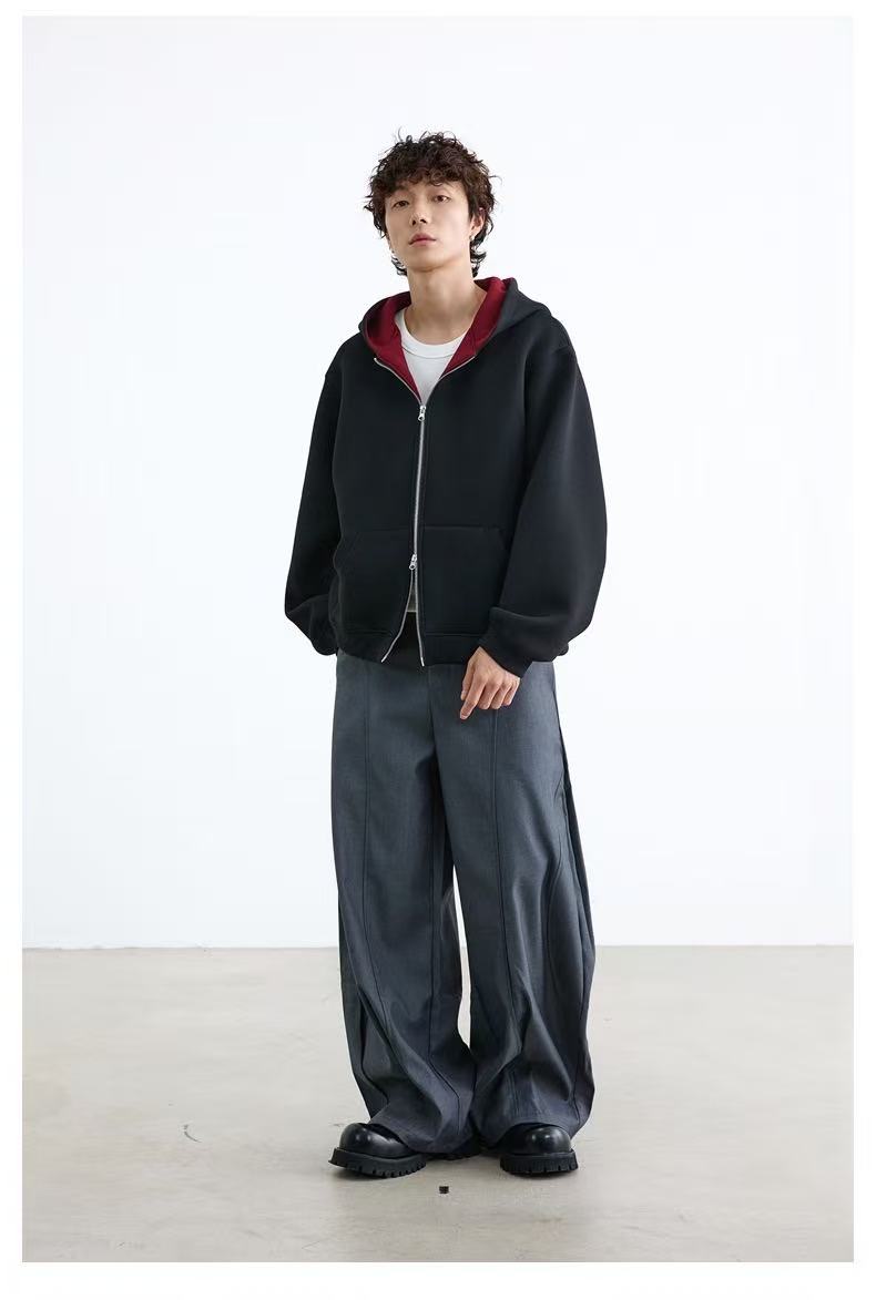 Full-body view of model wearing black zip-up hoodie with wide gray pants