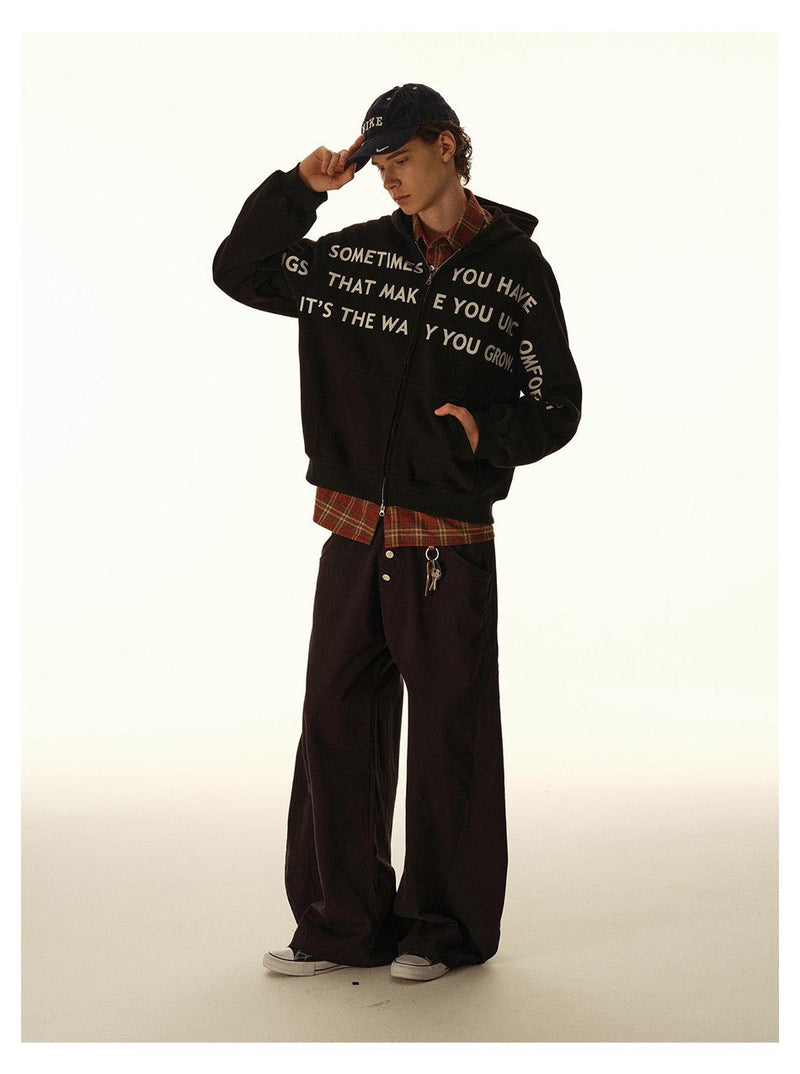Model in black slogan hoodie with hand touching cap brim