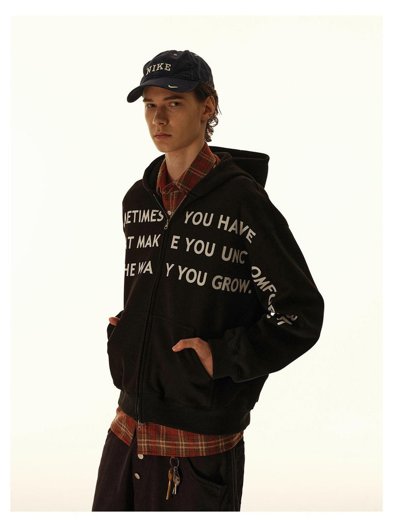 Three-quarter view of black zip-up hoodie with white slogan text