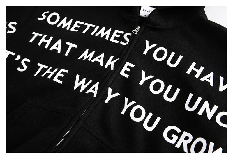 Close-up of black hoodie front with bold white slogan lettering