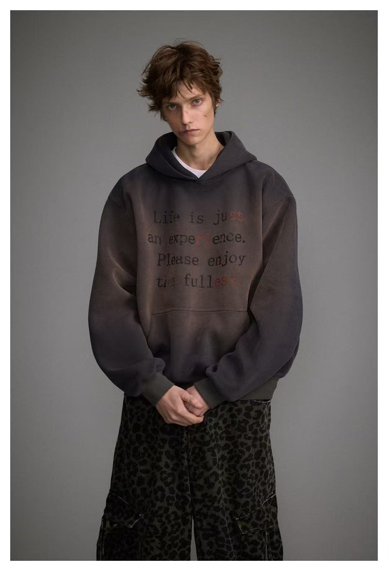 Front view of model wearing dark washed oversized hoodie with faded text print