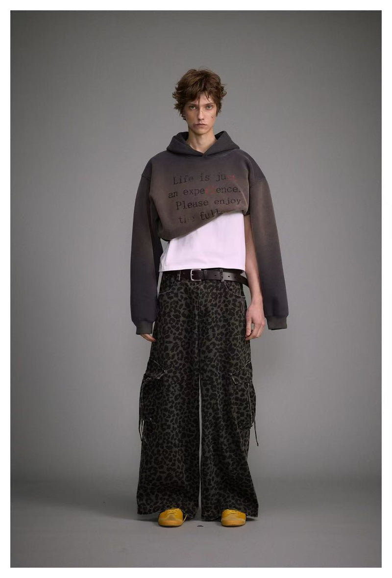 Full-length front view of oversized dark hoodie over white shirt and leopard-print pants