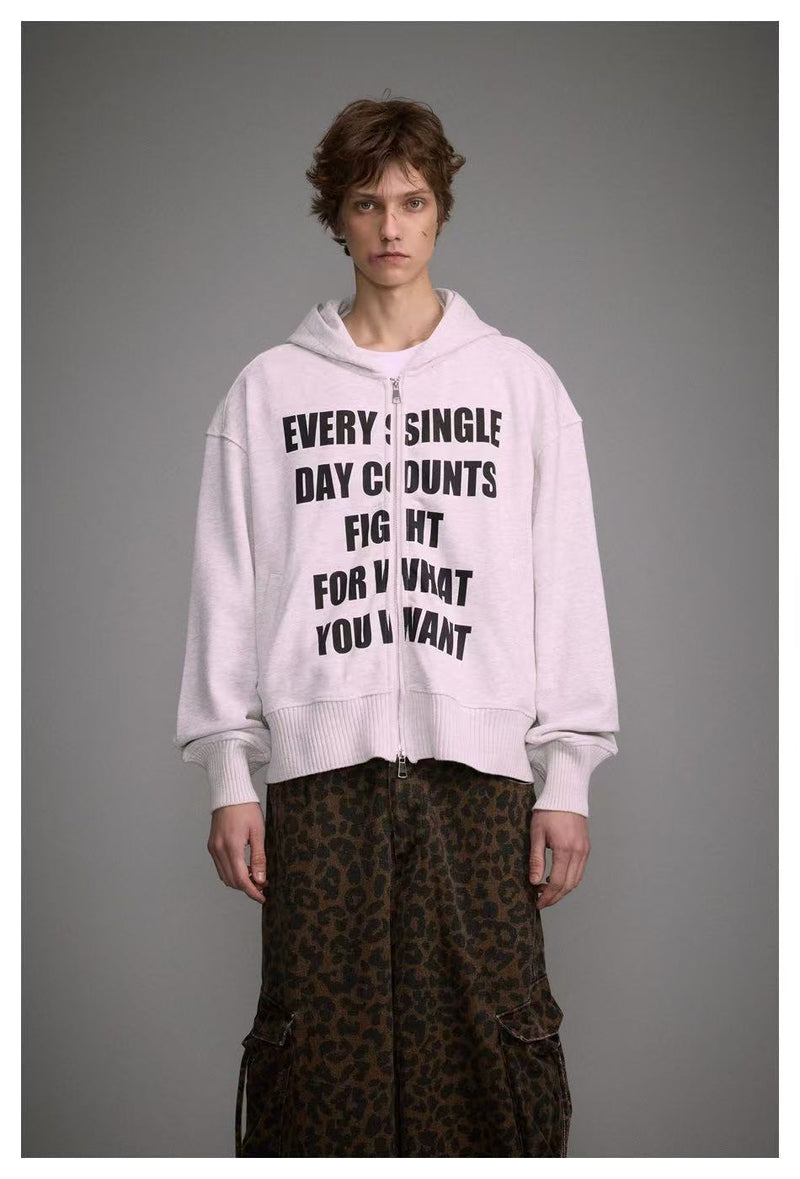 Close front view of white zip-up hoodie with bold black slogan print on model