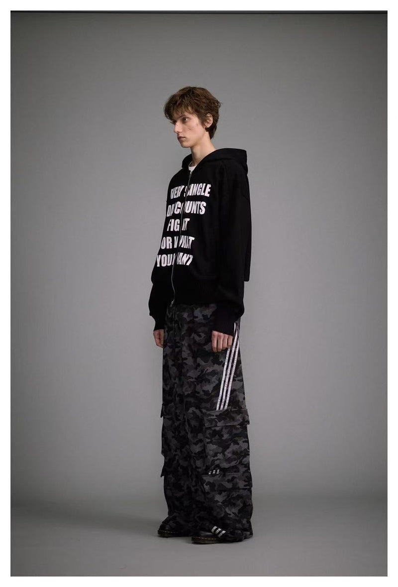 Side view of black zip-up hoodie with white slogan print on model