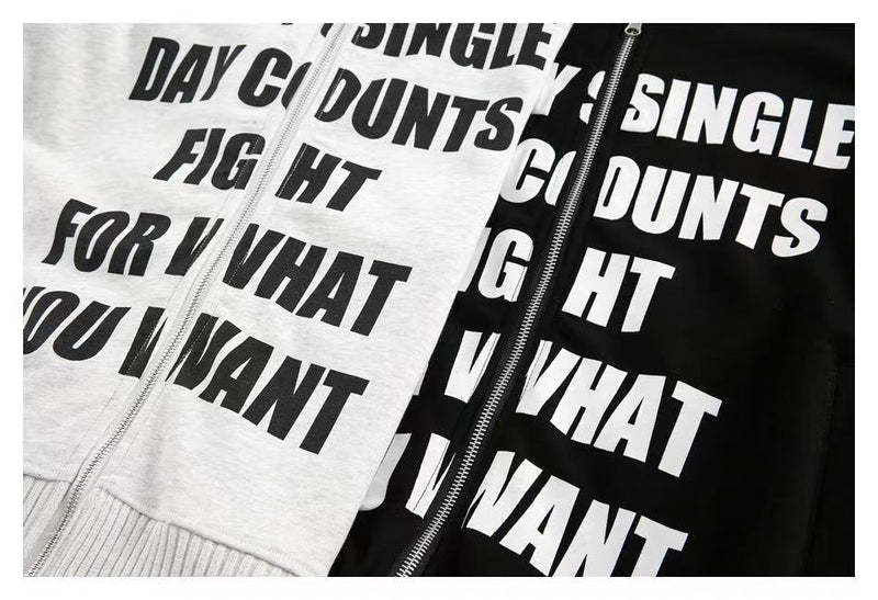 Close-up of white and black slogan hoodies with zipper and printed text