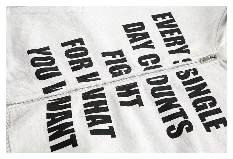 Close-up of white hoodie front with black slogan print and zipper