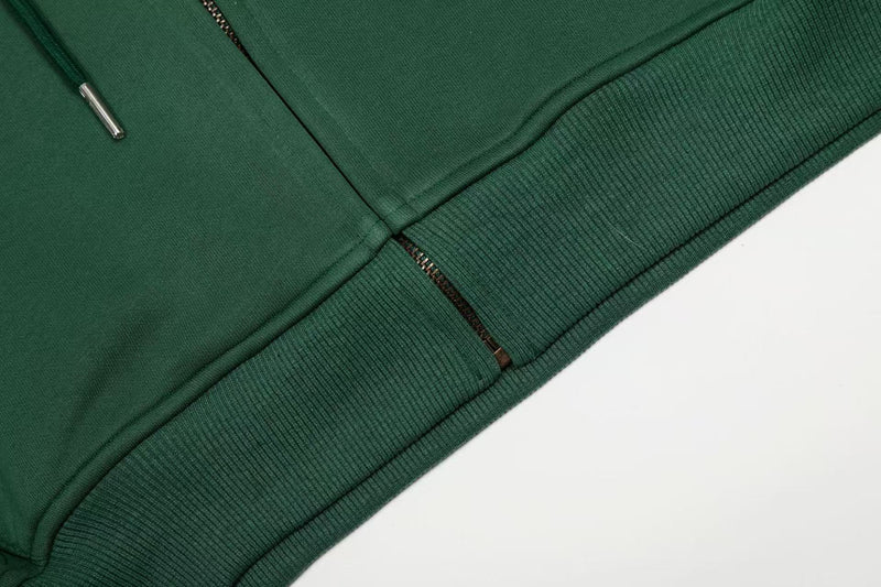Close-up of dark green hoodie hem and zipper with ribbed trim