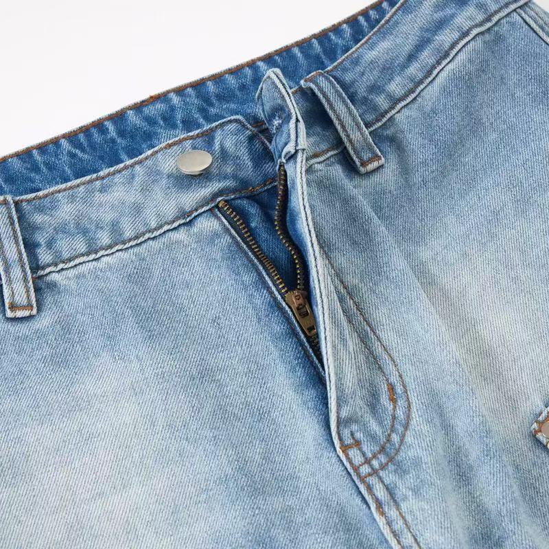 Close-up of light wash jeans front fly partially open with metal zipper