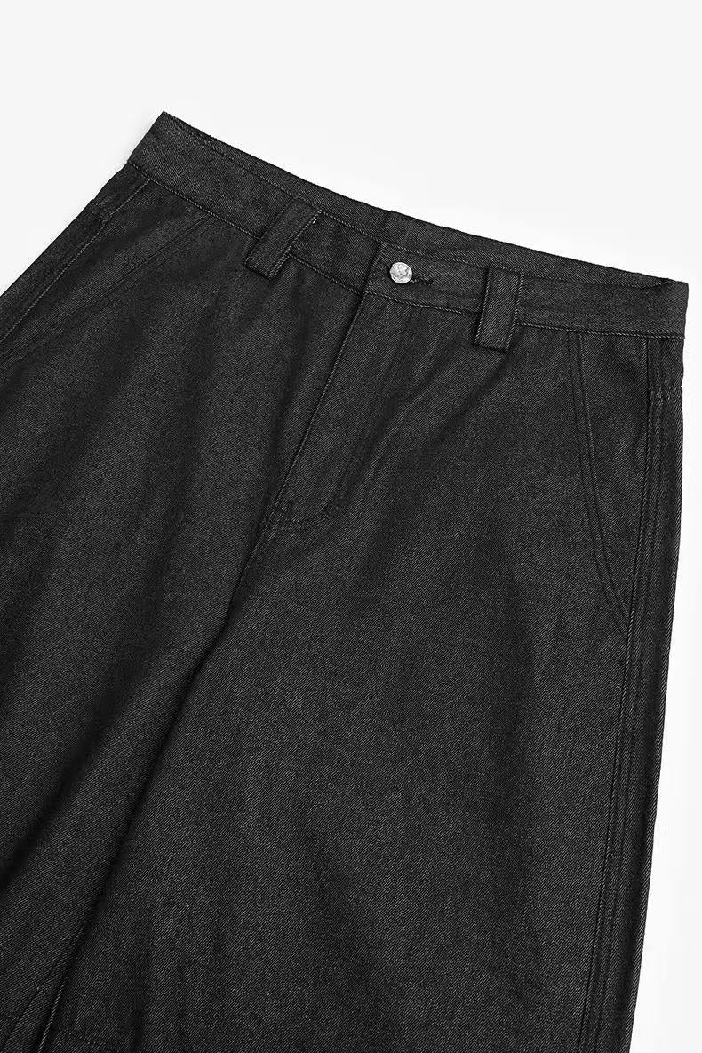 Close-up of the upper front of black wide-leg pants with waistband and button