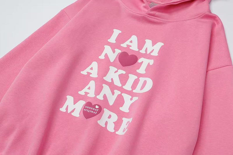 Angled front view of pink hoodie showing the stacked I AM NOT A KID ANY MORE graphic