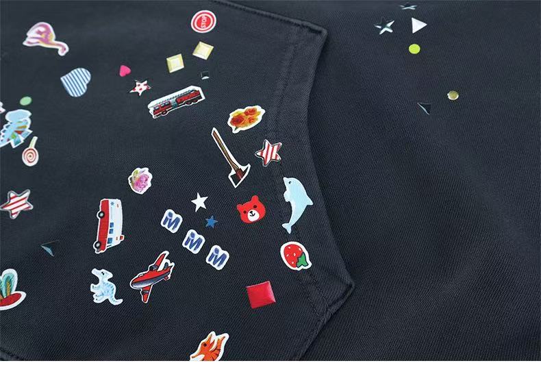 Close-up of black hoodie pocket and side front with scattered sticker-style print