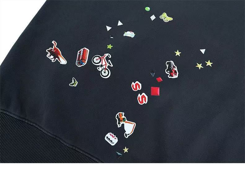 Close-up of black hoodie front with scattered sticker-style print near hem