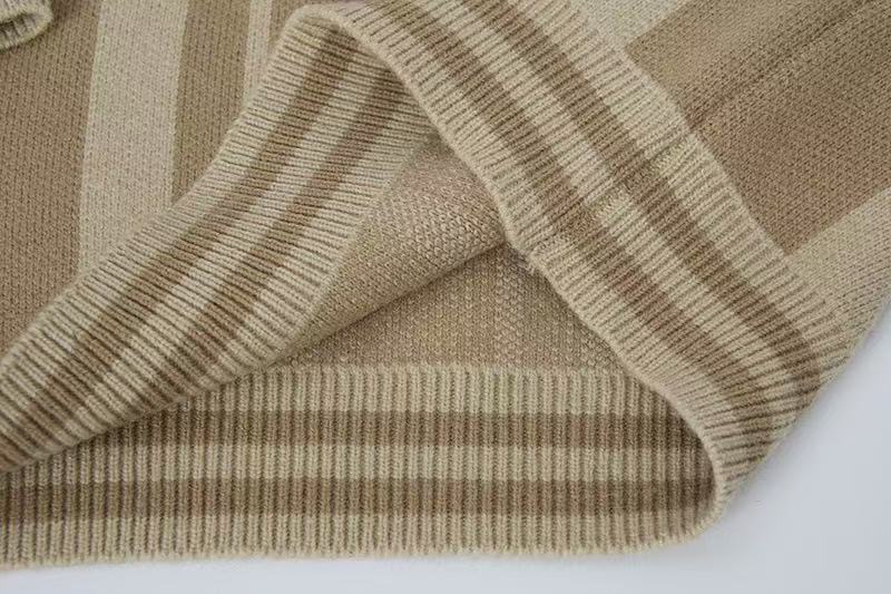 Close-up of the sleeve cuff and ribbed hem on a beige striped knit sweater