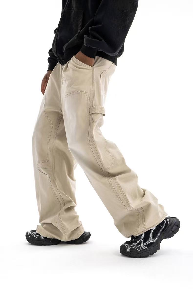 Beige wide-leg carpenter pants on model, side view with curved seam detailing and side loop