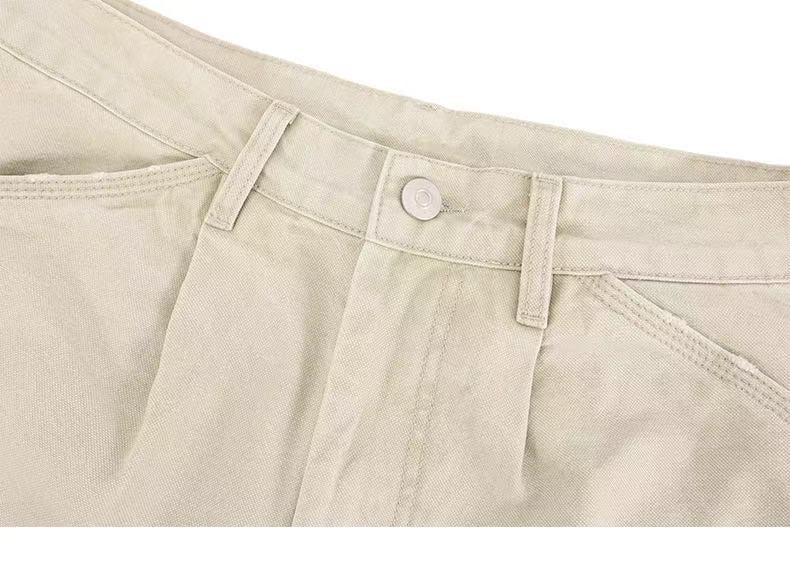 Beige pants waistband close-up with belt loops and button closure