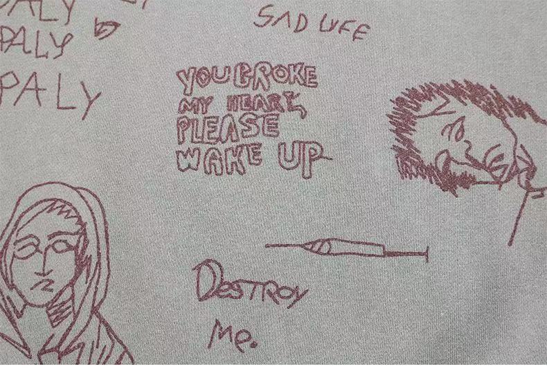 Close-up of light gray sweatshirt front graphic with handwritten text and sketched faces