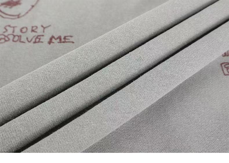 Close-up of light gray sweatshirt fabric folds with part of the printed back graphic visible