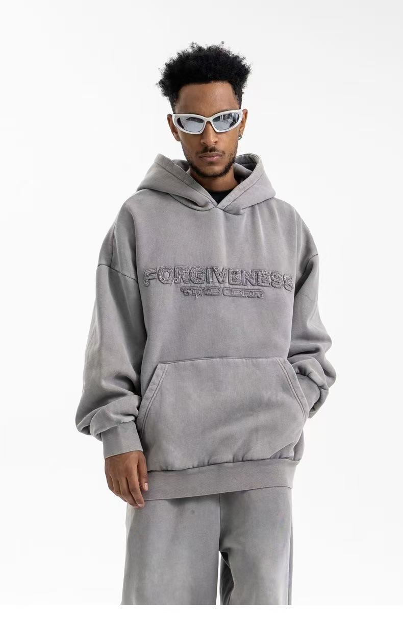 Chest-up front view of taupe hoodie with textured Forgiveness lettering and kangaroo pocket