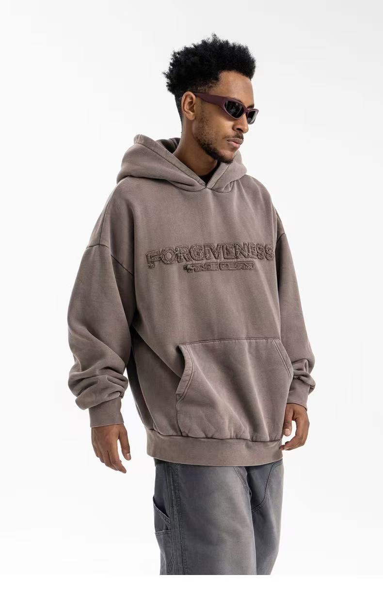 Front angled view of brown-gray oversized hoodie with Forgiveness embroidery and wide sleeves
