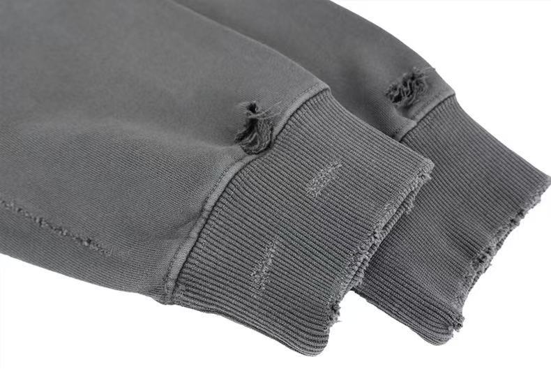 Close-up of gray hoodie cuffs with ribbed sleeves and worn frayed holes