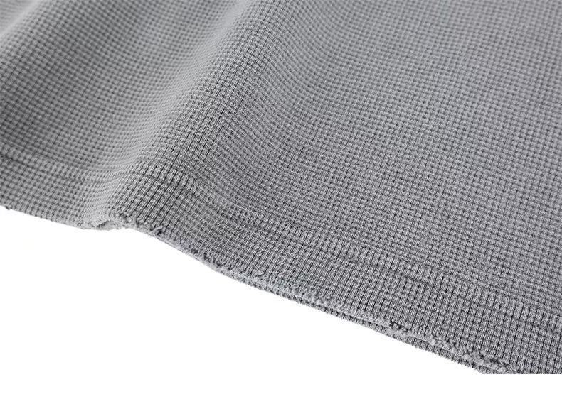 Close-up of gray crewneck hem with frayed edge and ribbed texture