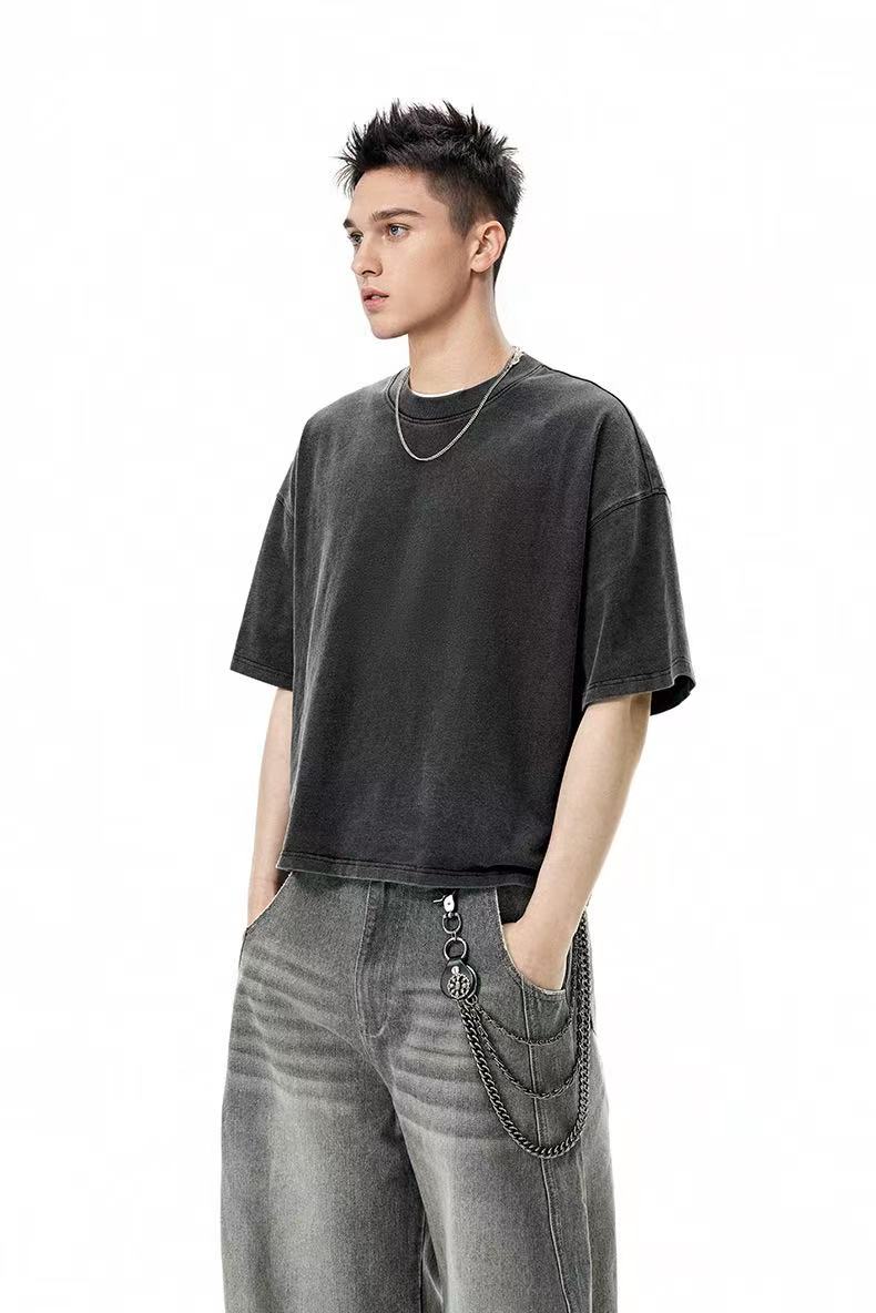 Model wearing an oversized washed black heavyweight cotton tee with wide gray jeans and chain detail