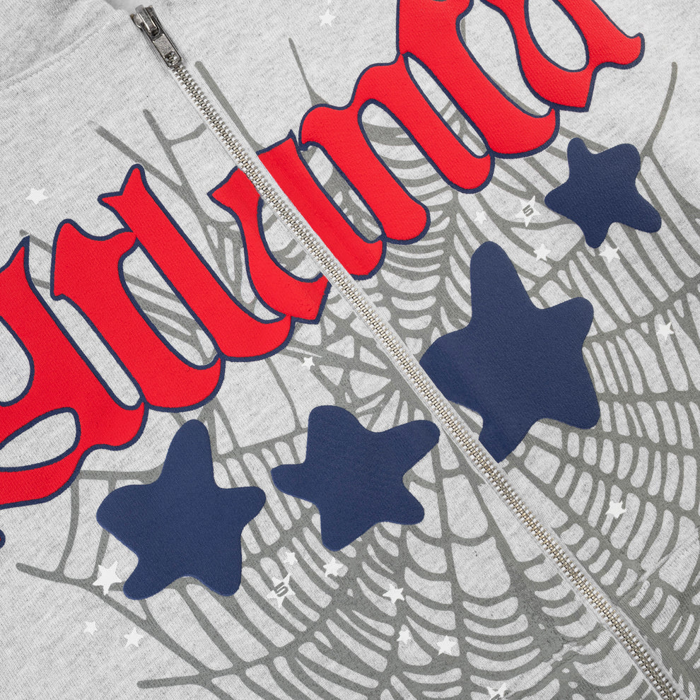 Close-up of the Sp5der Atlanta Web Zip Hoodie – Grey 440GSM Heavyweight Streetwear, showcasing bold red Gothic lettering, navy stars, a gray spiderweb graphic in the background, and white star accents for an eye-catching look.