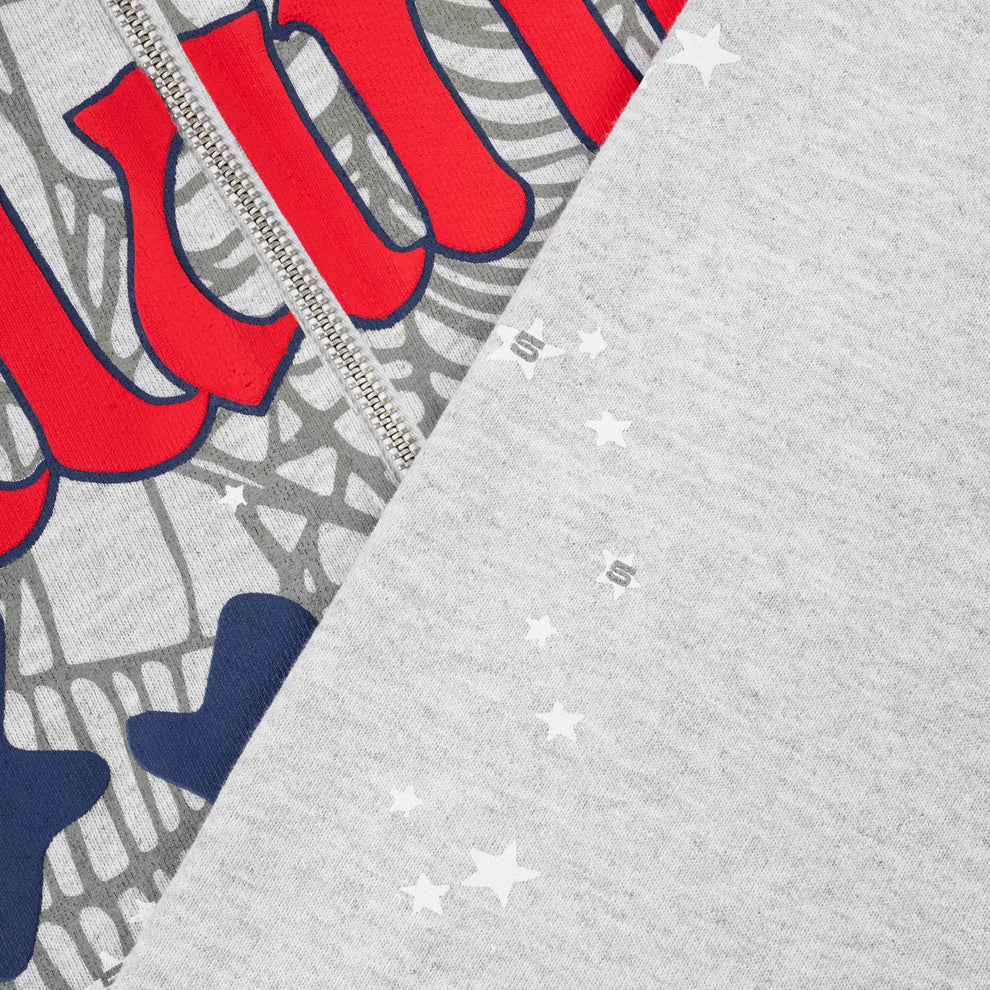 Close-up of the Sp5der Atlanta Web Zip Hoodie – Grey 440GSM Heavyweight Streetwear, showcasing a zipper, bold red and navy graphic design with web patterns and white star details—ideal for streetwear enthusiasts.