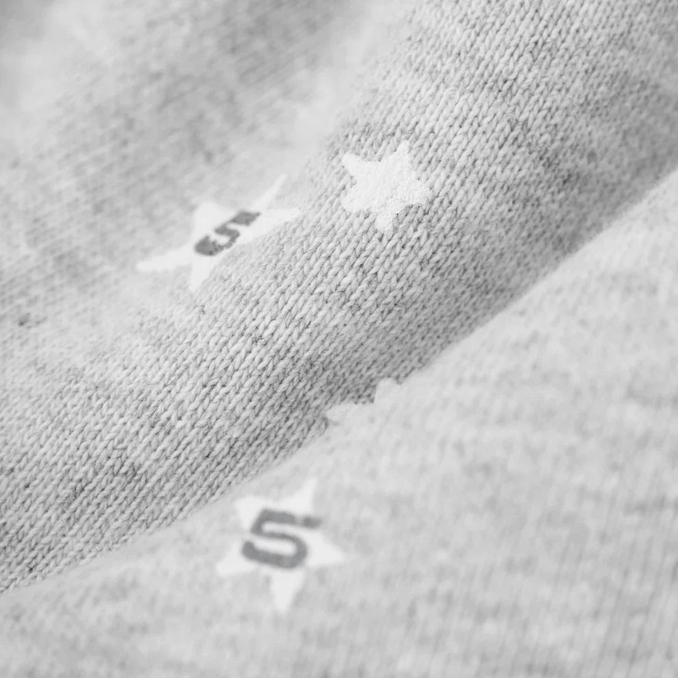 Close-up of light gray knit fabric with small white stars and the number 5 from the Sp5der Atlanta Web Zip Hoodie – Grey 440GSM Heavyweight Streetwear.
