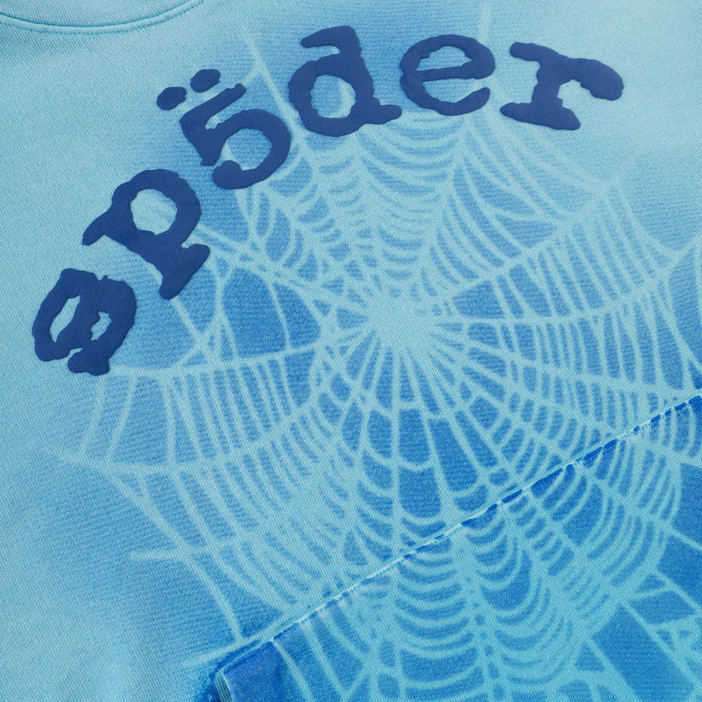 Close-up of the Sp5der “Blue Venom” Web Hoodie, an oversized streetwear pullover in Sky Blue Fade, crafted from 440GSM heavyweight cotton fleece with a spiderweb design and dark blue sp5der logo.