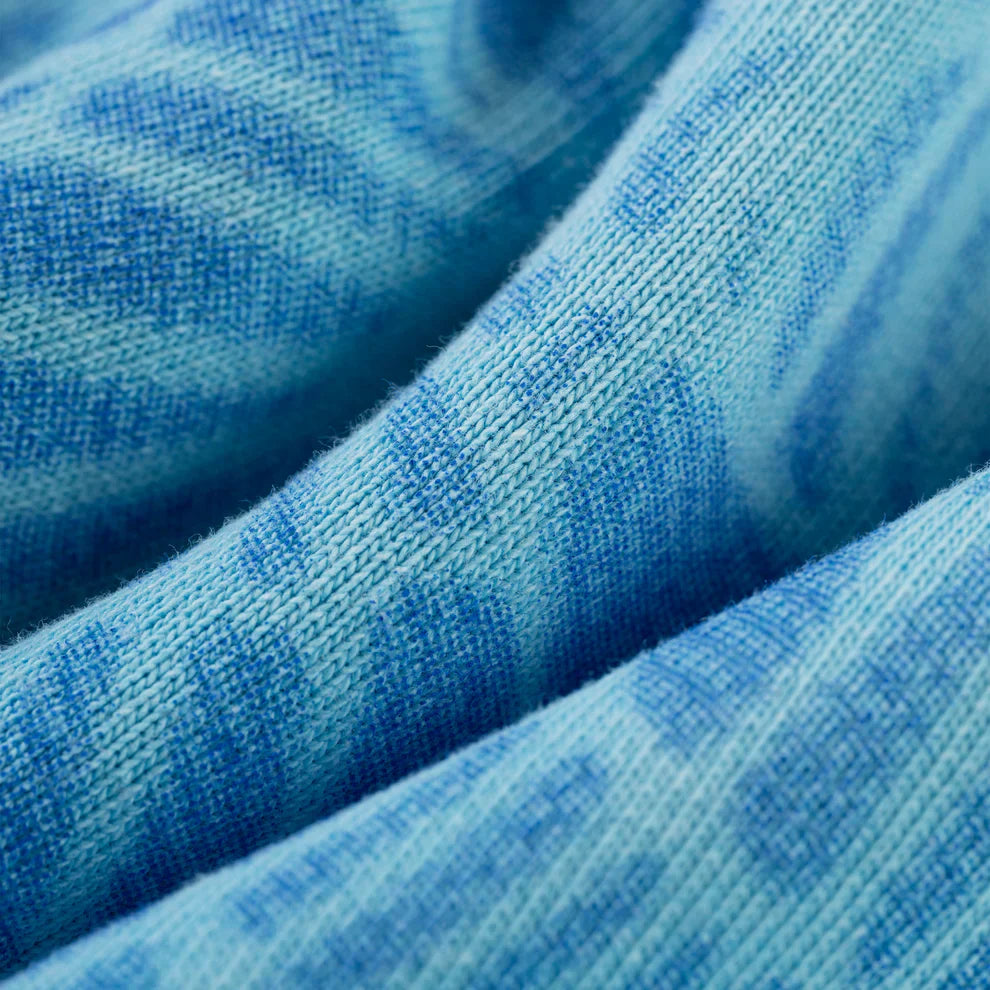 Close-up of the Sp5der “Blue Venom” Web Hoodie – Sky Blue Fade, showing its wavy tie-dye pattern and heavyweight 440GSM cotton fleece with a visible knit texture. The oversized streetwear pullover looks soft and stylishly folded.