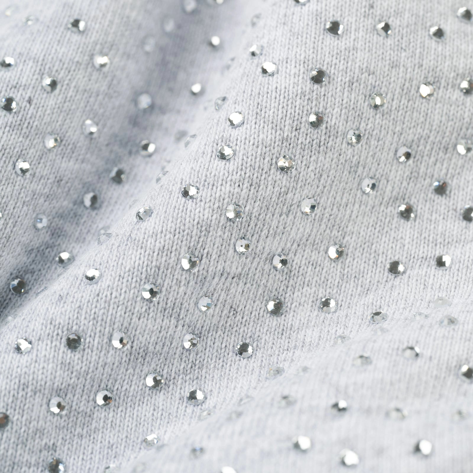 Close-up of the Grey Sp5der Rhinestone VVS Hoodie 440GSM, featuring soft light grey fabric with all-over shiny silver rhinestones for a sparkling, textured look. The Grey Crystal Sp5der Hoodie offers comfort with gentle fabric folds.